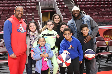 A group of parents, staff and students, smiling for a photo courtside at a Harlem Globetrotters event.