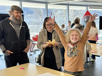 Family fun at a Pi Day event at Carnegie Science Cente. A student proudly shows off their handiwork as adults look on with amusement and pride.