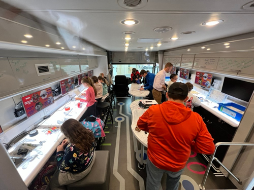 Parents and students working on STEM kits aboard the Reach STEM bus.