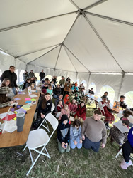 Reach's 'Bat day' event: a group of staff, students, and parents engaging in crafts and activities under a large white tent.