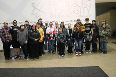 Group of Reach staff, students, and parents posing for a photo in the lobby of harrisburg university of science and technology.
