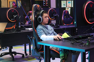 A student wearing headphones is focused intently on the screen while playing a game at the 'eSports in Person' event hosted by Harrisburg University and the Whitaker Center.