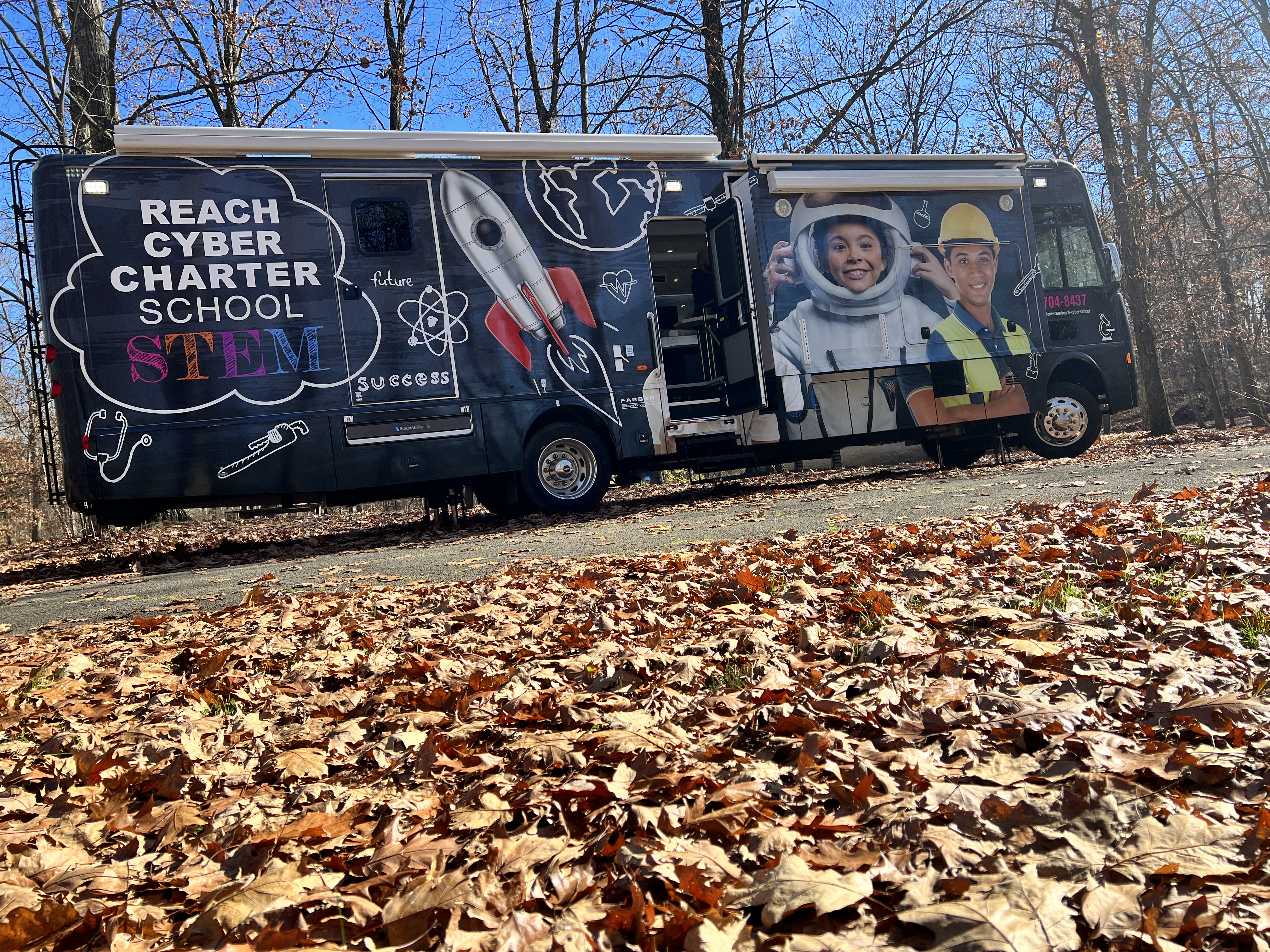 The Reach Cyber STEM bus parked on a road in the middle of a forest.