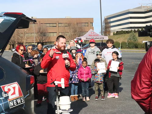 A group of Reach students, parents, and staff gathered as a reporter from abc27 films news story about the educational event taking place at Reach HQ.